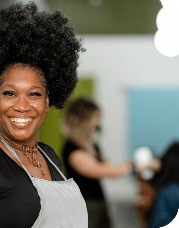 Smiling woman in apron, possibly a small business owner or chef.